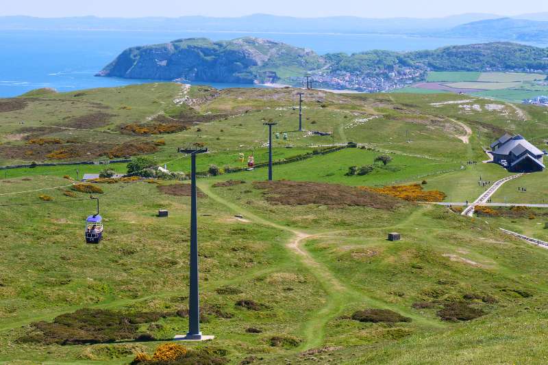 Cable cars carrying passengers over the Great Orme in Llandudno with scenic views
