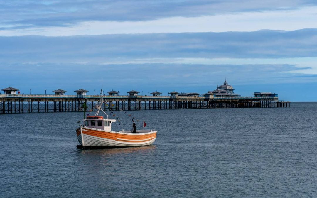 Small boat in Llandudno bay with Llandudno pier in the background